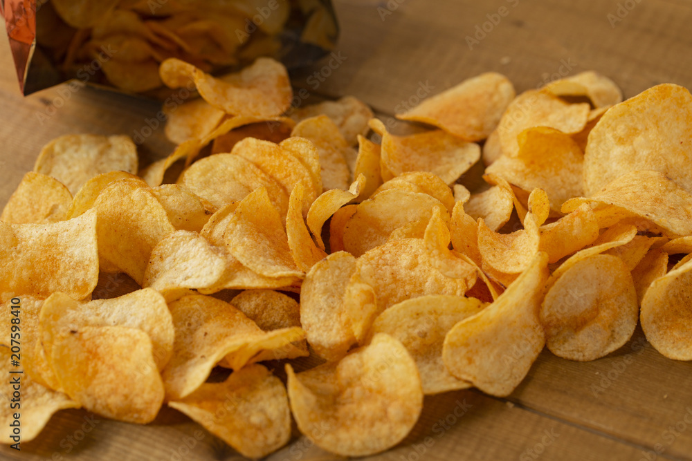 Potato chips, top view. Salty crisps scattered on a table.
