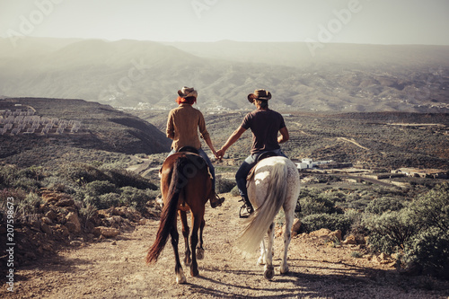 love and friendship concept outdoor for people ride horses in the countryside. amazing landscape and a world to discover traveling together. caucasian man and woman