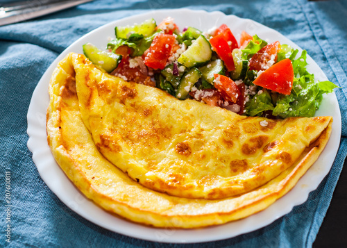 Omelet with vegetable salad in white plate on table