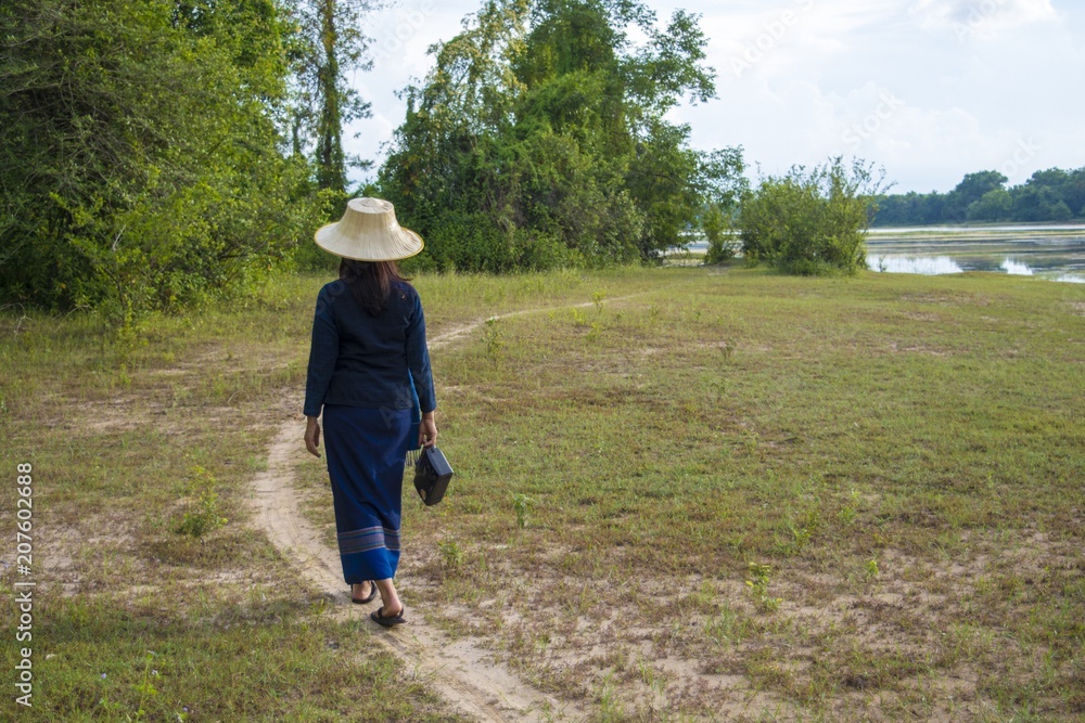 Asian peasant lifestyle with transistor radio/Asian women carrying transistor radio walk along the pathway in the meadow. Asian peasant lifestyle with transistor radio/Asian women carrying transistor radio walk along the pathway in the meadow.