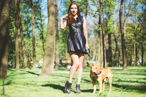A beautiful girl is walking with a sharpei dog