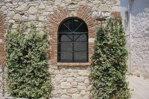 Arch shaped iron framed window of a stone brick house