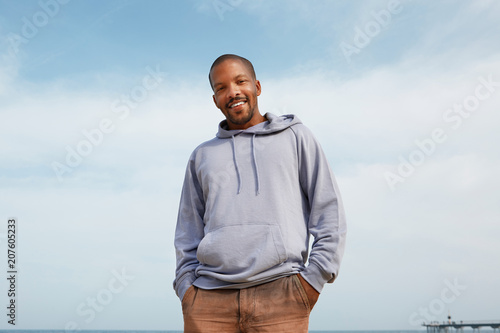 Summer active sports concept. Smiling happy young African-American man hipster in sport hoody on the beach