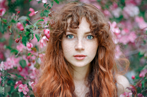 Summer portrait of young tender girl, ginder hair, redhead young girl with freckled skin. Caucasian girl posing in flowers