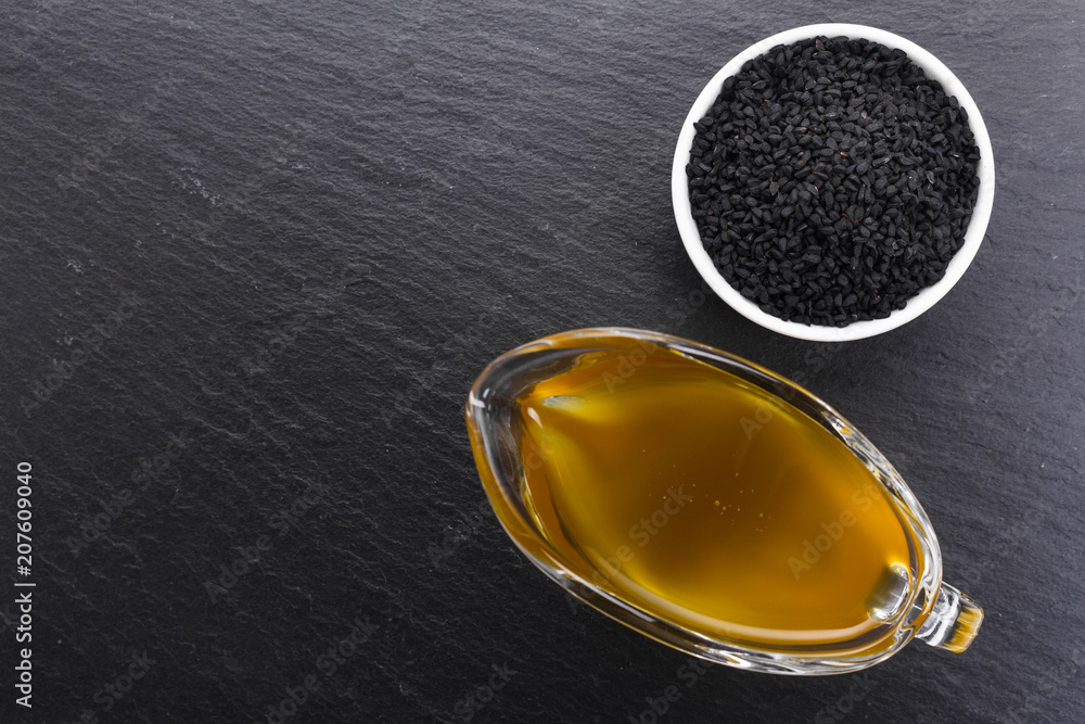 grains of black cumin and oil on the rustic background grains of black cumin and oil on the rustic background