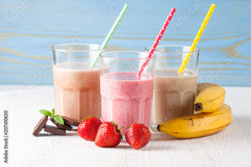 Glasses of milkshakes with chocolate, strawberry, banana flavor, with ice cream on wooden blue and white background. Sweet drinks for summer concept. Shakes and smoothies. Milk shake and cocktail. photo