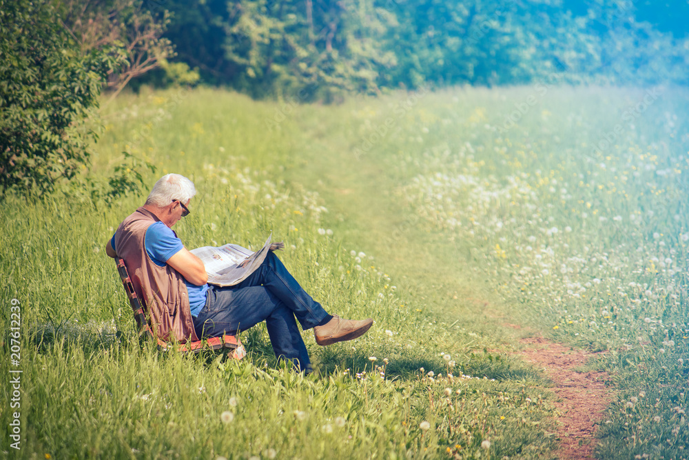 gray haired man reading newspaper outdoor, image with copy space gray haired man reading newspaper outdoor, image with copy space