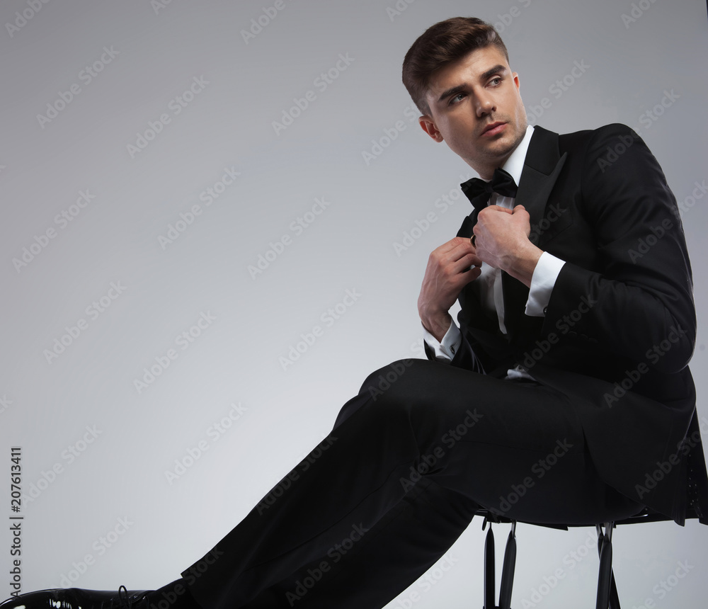 handsome young man fixing suit collar and looking to side Stock Photo |  Adobe Stock