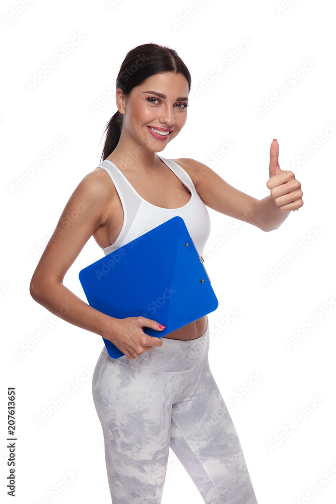 beautiful fitness woman with blue clipboard makes thumbs up sign beautiful fitness woman with blue clipboard makes thumbs up sign