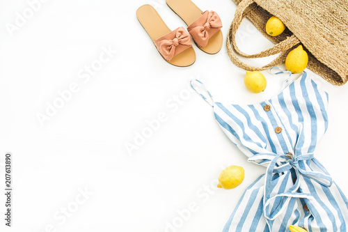 Summer female fashion stylish composition. Dress, slippers, straw, lemons, tulip flower and accessories on white background. Flat lay, top view.