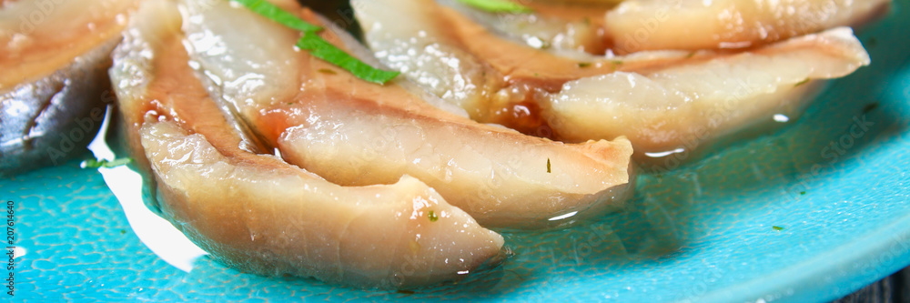 Marinated herring in oil on a wooden board on a gray dark table. Snack. Top view. Copy space. Marinated herring in oil on a wooden board on a gray dark table. Snack. Top view. Copy space.