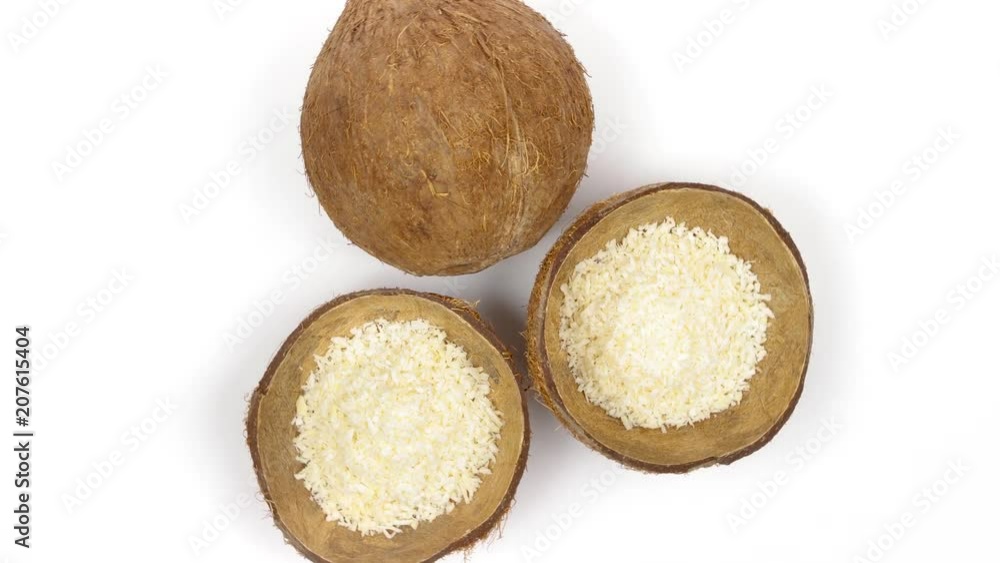 Top view of one whole and two shells halves of tropical coconut with dried white coconut flakes rotating on white isolated background. Healthy tropical fruits. Loopable seamless cocos rotating Top view of one whole and two shells halves of tropical coconut with dried white coconut flakes rotating on white isolated background. Healthy tropical fruits. Loopable seamless cocos rotating