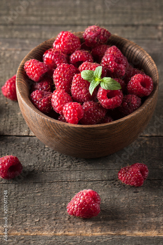 Ripe fresh sweet raspberries in a wooden bowl on wooden table background.