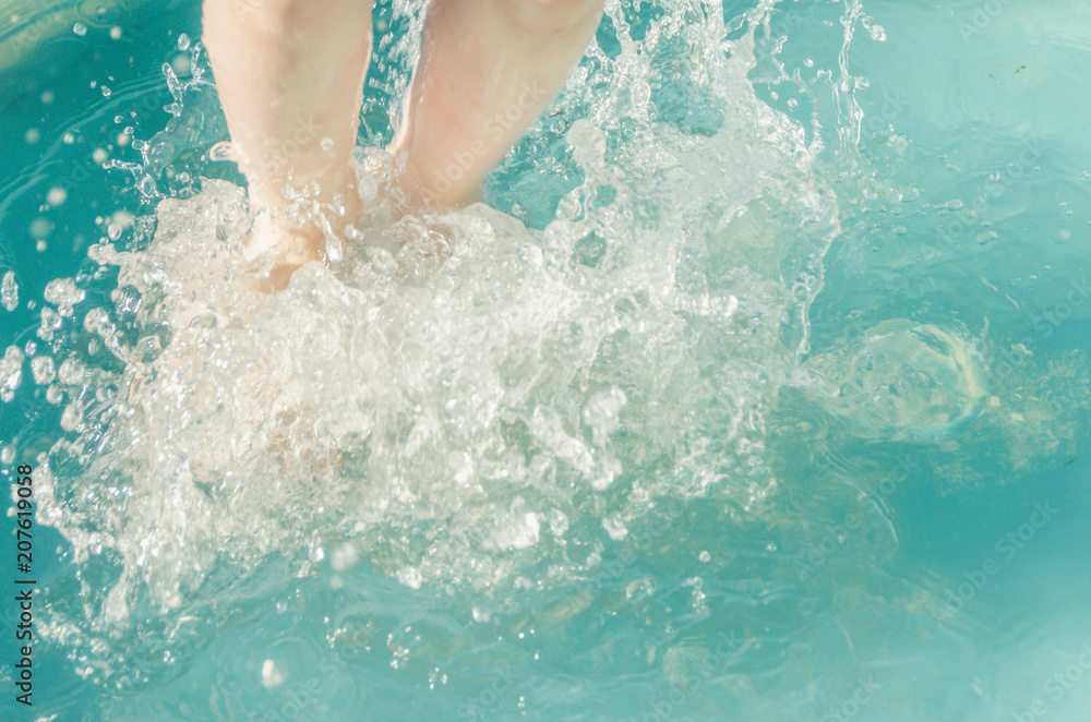 close-up, baby feet in the water in a jump spray