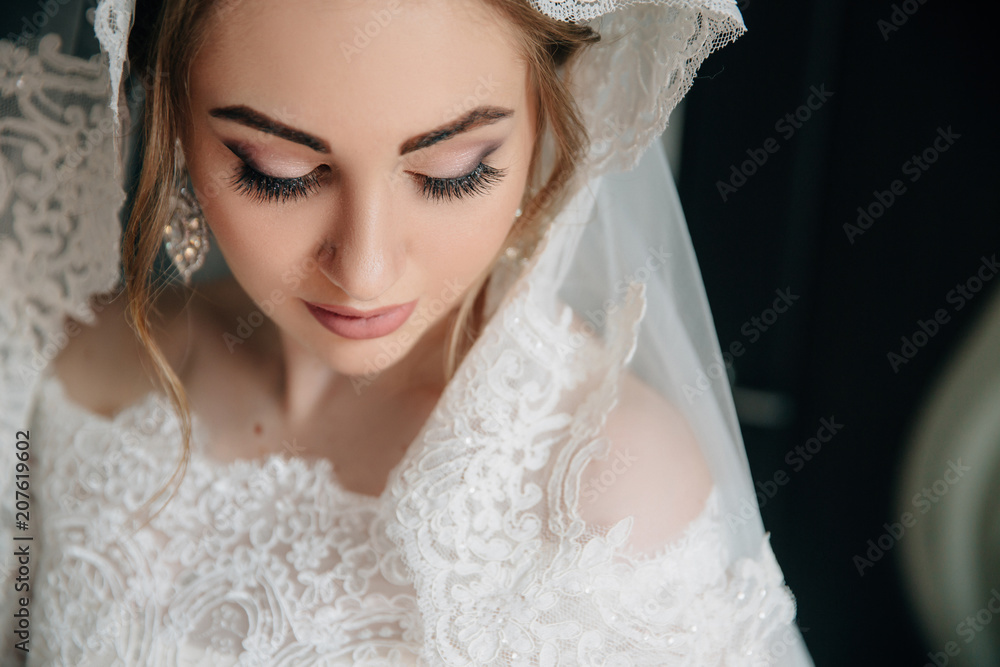 Close-up of a girl face that looks down. Beautiful natural make-up of eyes, long thick eyelashes, white large earrings with stones. Close-up of a girl face that looks down. Beautiful natural make-up of eyes, long thick eyelashes, white large earrings with stones.