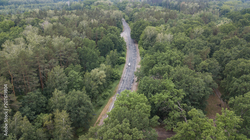 aerial view over road between forests
