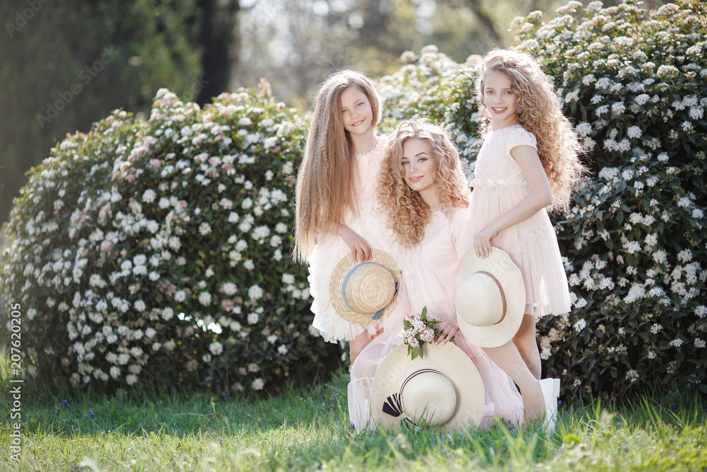 Φωτογραφία The older sister and her two younger sisters spend time outdoors in a beautiful Park with flowering shrubs