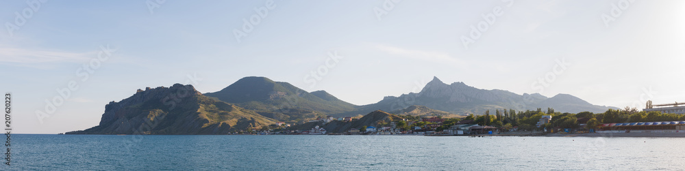 Panorama of the coastal zone of the city of Koktebel with a view of the Karadag mountain at sunset. Crimean nature. Crimean tourism.