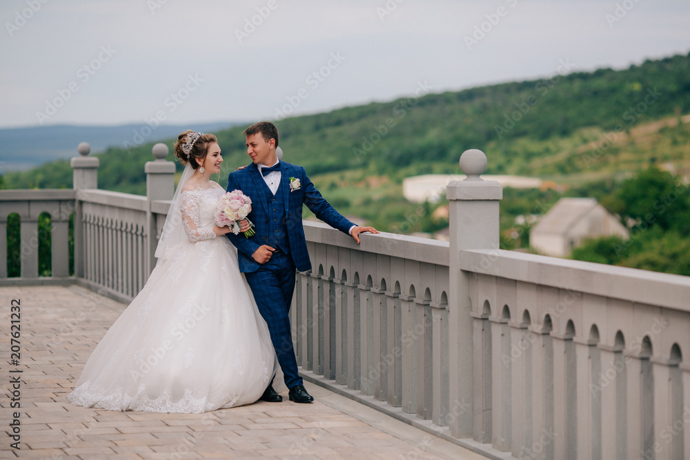 The bride and groom are walking along the viewing platform, laughing and smiling at each other and sharing their impressions of the wedding day. The bride and groom are walking along the viewing platform, laughing and smiling at each other and sharing their impressions of the wedding day.