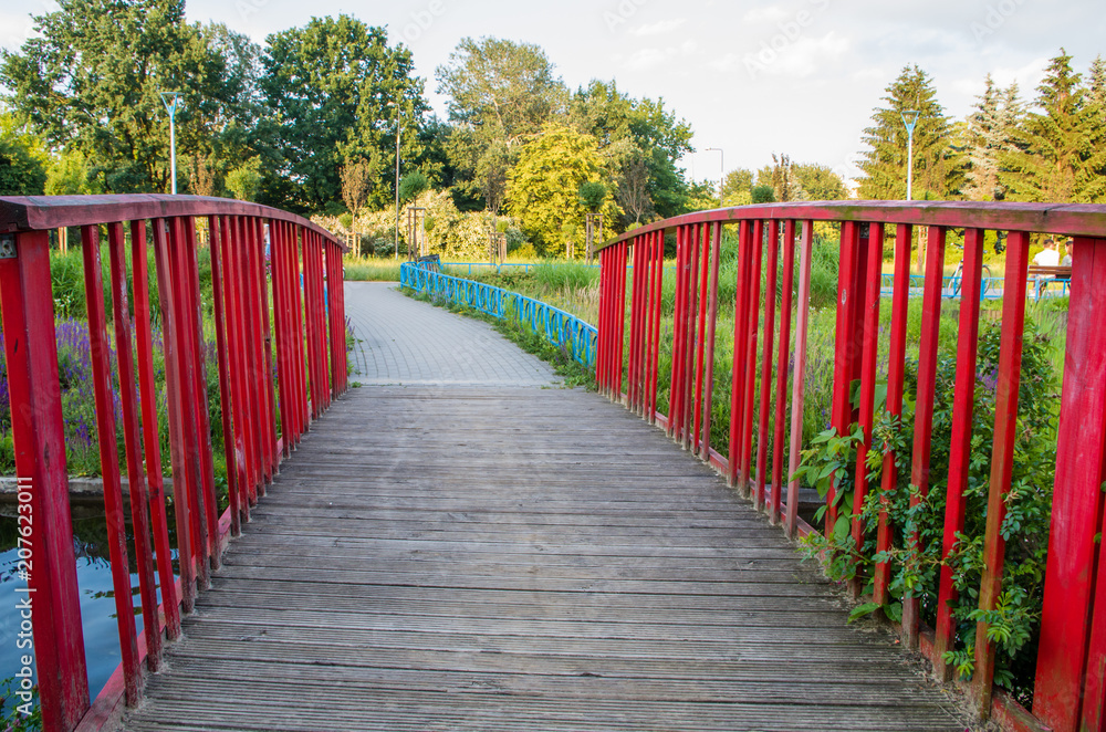 Red wooden footbridge on the pond in the park Red wooden footbridge on the pond in the park