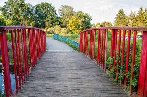 Red wooden footbridge on the pond in the park