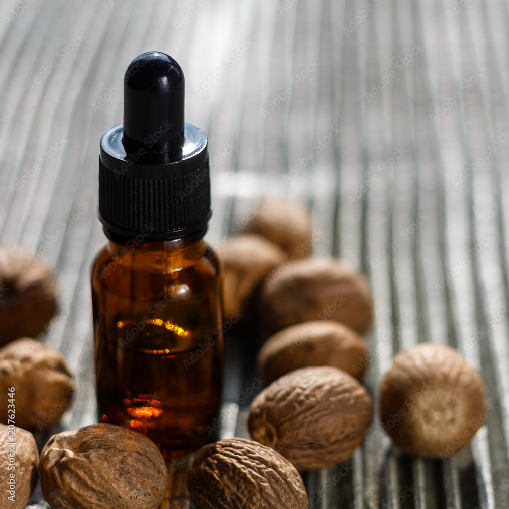 nutmeg essential oil on a gray wooden background nutmeg essential oil on a gray wooden background