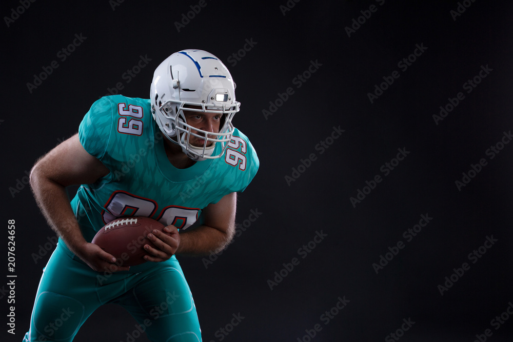 Portrait of American football player holding a ball in both his arms. Copy space. Rugby Portrait of American football player holding a ball in both his arms. Copy space. Rugby