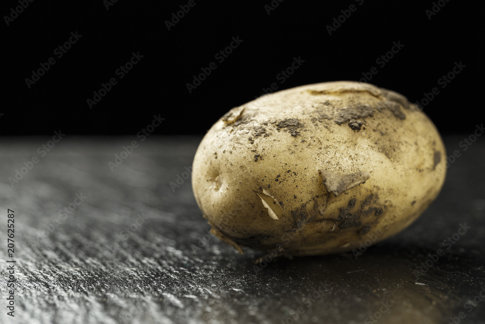 raw young potatoes on a black background raw young potatoes on a black background
