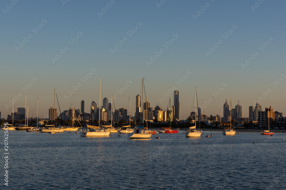 Sailing boats moored in St Kilda with the Melbourne skyline in the background.