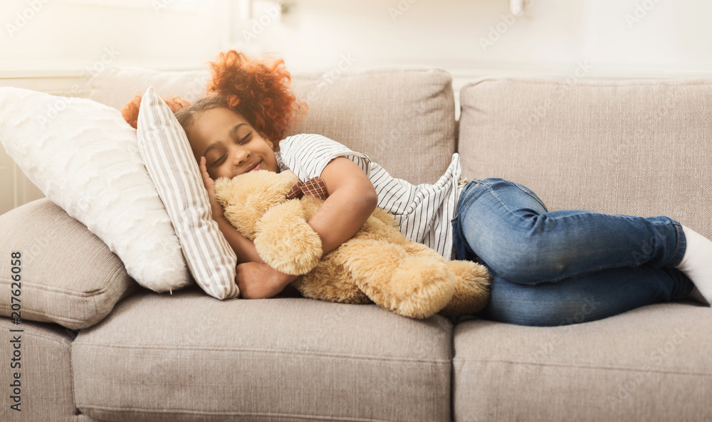 Little happy african-american girl sleeping on couch at home Little happy african-american girl sleeping on couch at home