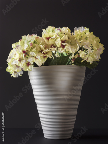 Fototapeta Naklejka Na Ścianę i Meble -  Fake flowers in a vase of white color on a black background
