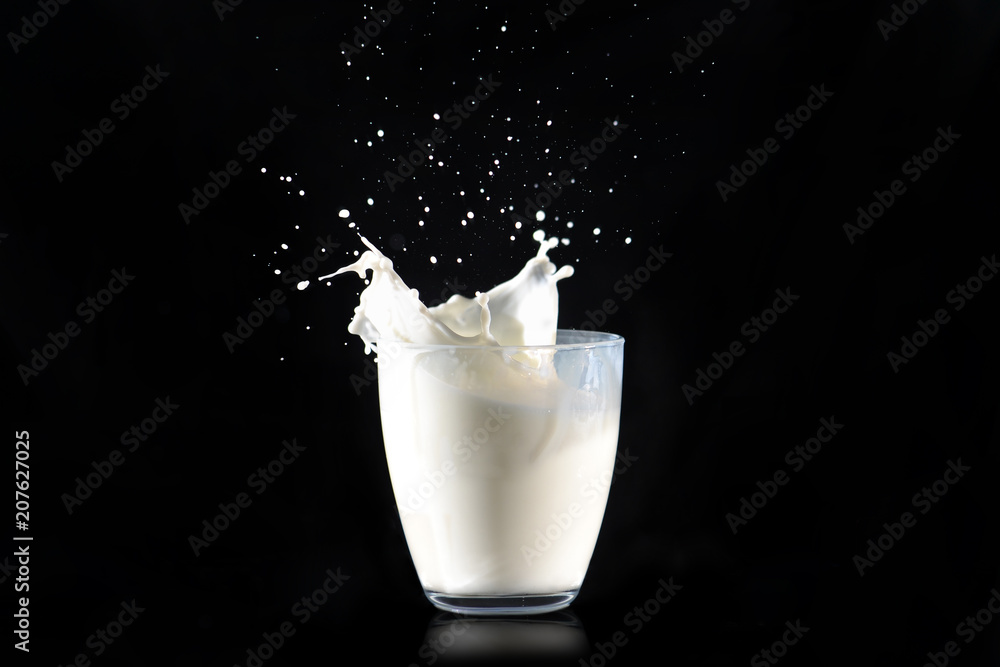Milk splashes from a glass transparent glass on a black background.