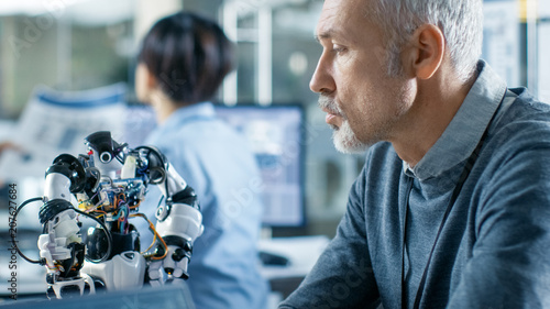 Robotics Engineer Manipulates Voice Controlled Robot, Laptop Screen Shows Speech and Face Recognition Software. In the Background Robotics Reseatch Center Laboratory. photo