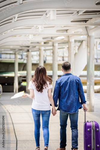Asian couple tourist has walking and travelling with big purple bag and hand holding to travel together.