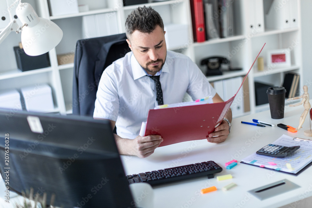 A man is sitting at the desk in the office and working with documents. A man is sitting at the desk in the office and working with documents.