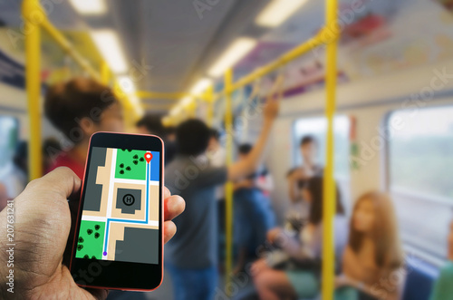 hand using mobile phone for navigating map interface application with blurred view of people in subway train, internet connection, communication technology, transportation and travel concept