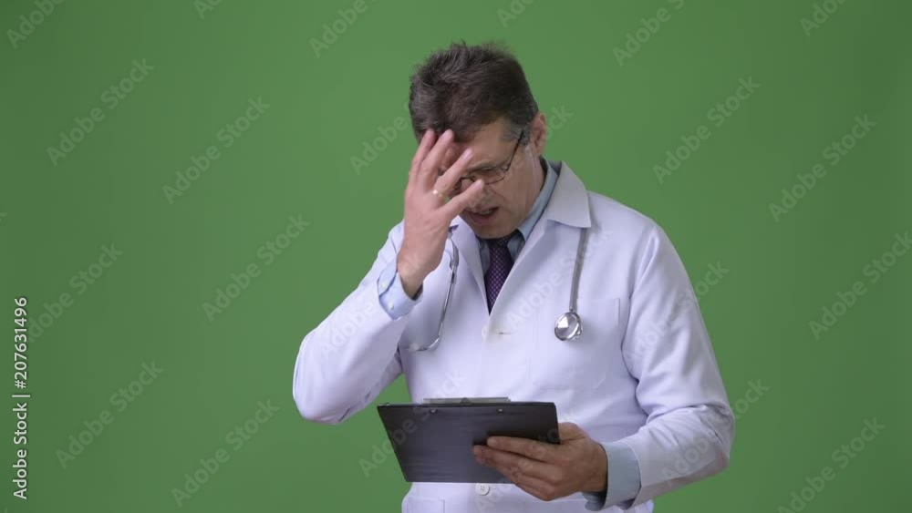 Mature handsome man doctor against green background Mature handsome man doctor against green background