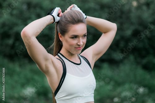 Young woman wearing sportwear touching her hairstyle outdoor. Close-up portrait