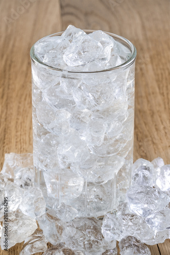 Glass of cold water with ice on wooden table