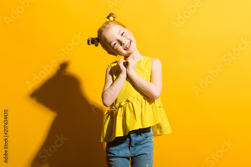 Girl with red hair on a yellow background. The girl clasped her heart. © Ivan Traimak