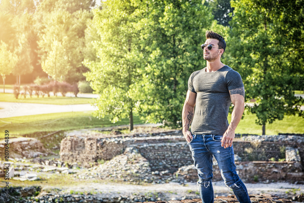 Fototapeta premium Handsome muscular man with tattoo posing in European luxury garden in Turin, Italy
