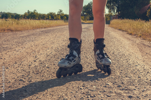 teenage girl rollerblading on the street on the road in the countryside on a summer evening at sunset close-up of a foot with a copy space