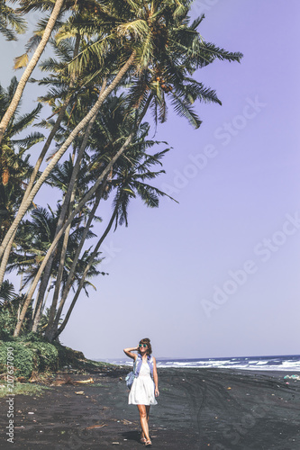 Young woman on a black sand beach, Bali island.