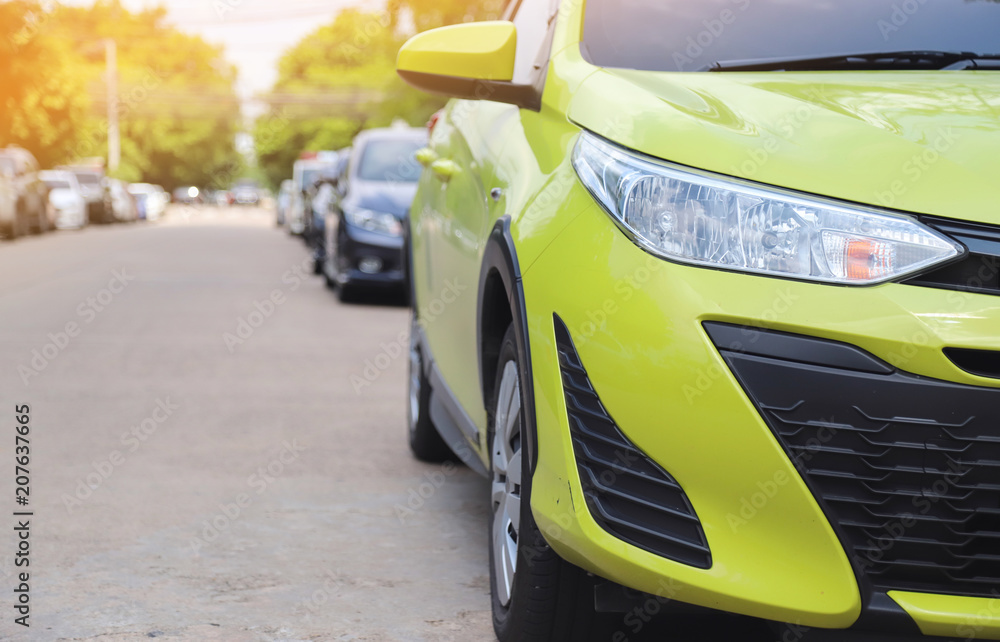 Closeup of front side of yellow green car parking beside the street in sunny day. Closeup of front side of yellow green car parking beside the street in sunny day.