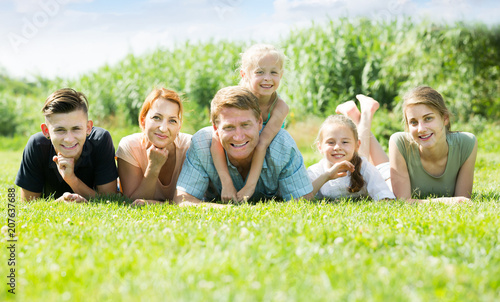 Cheerful man and woman with kids lying in park