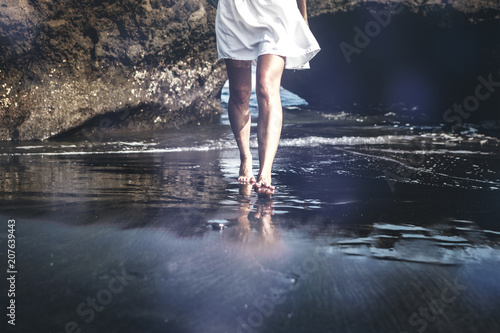 Young woman on a black sand beach, Bali island.