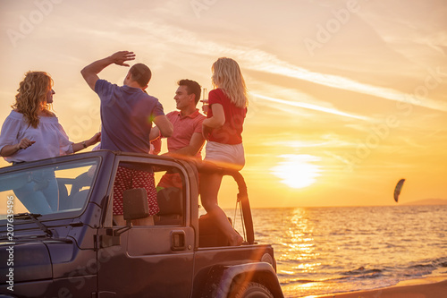 Young people having fun in convertible car at the beach at sunset. © blicsejo