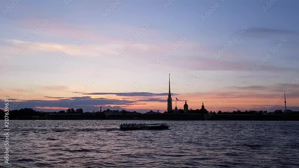 White nights in St. Petersburg. Historic centre. The ship floats on the Neva river. Silhouette of the Peter and Paul fortress against the purple sunset. A romantic evening in a beautiful city White nights in St. Petersburg. Historic centre. The ship floats on the Neva river. Silhouette of the Peter and Paul fortress against the purple sunset. A romantic evening in a beautiful city