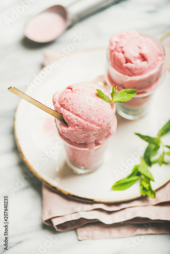 Healthy low calorie summer dessert. Homemade strawberry yogurt ice cream with fresh mint in glasses on plate over grey marble table background. Clean eating, dieting food concept
