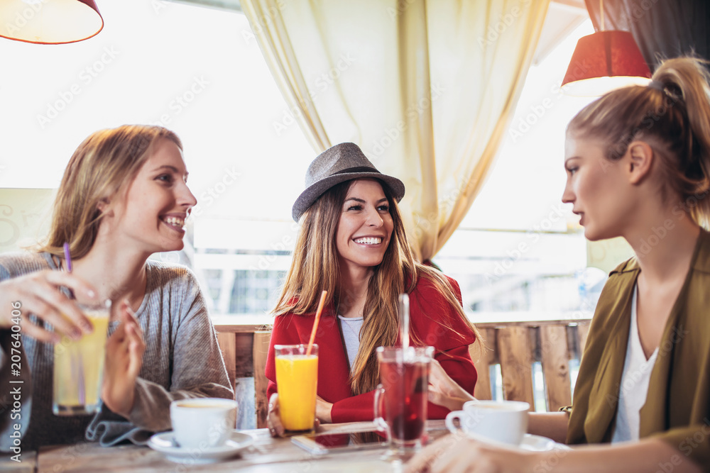 Female friends enjoying in conversation and drinking coffee in cafe Female friends enjoying in conversation and drinking coffee in cafe